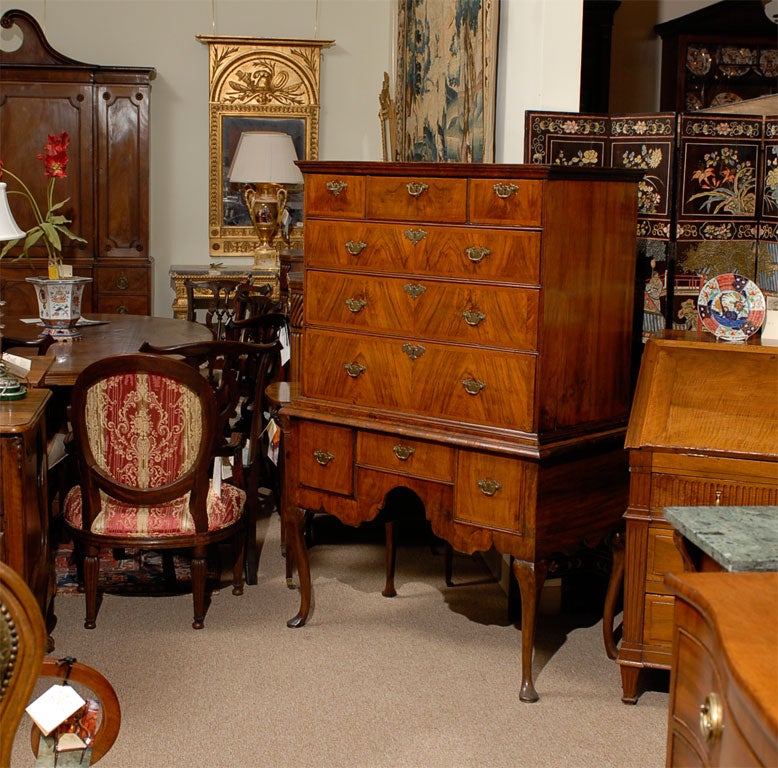 A George I Highboy, the exterior in highly-figured Walnut veneers, dating from the first quarter of the 1700s. <br />
<br />
The frame in two sections, a lower three-drawer cabinet over an exaggerated shaped apron, supported atop cabriole legs
