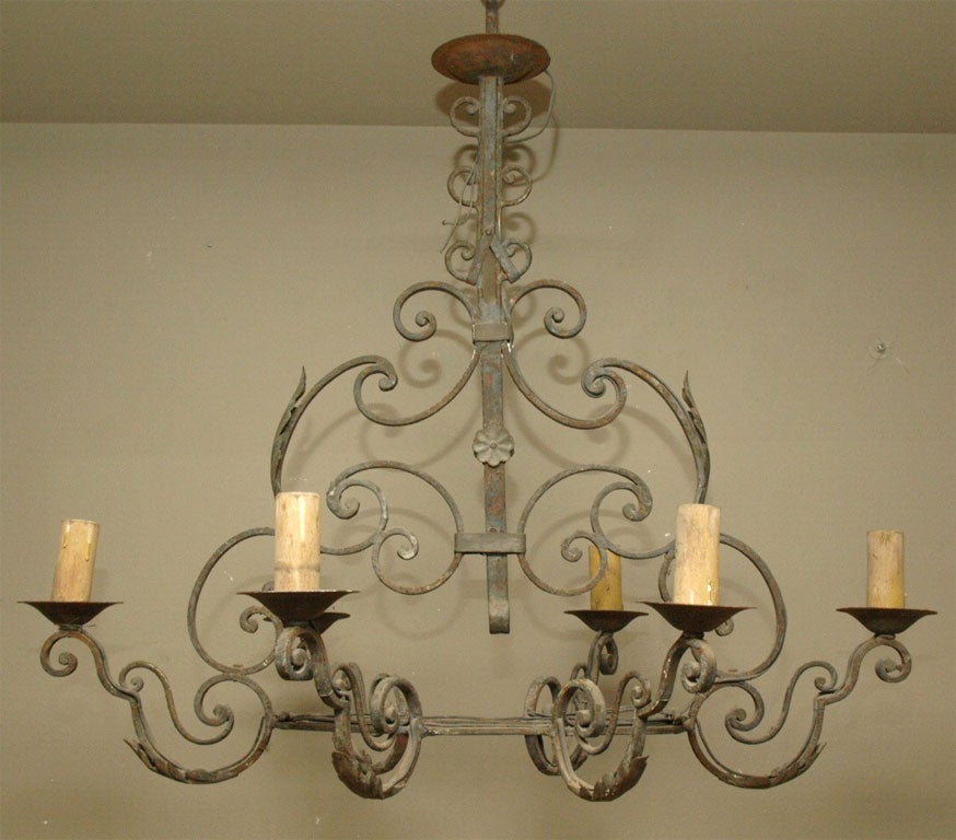 Wrought iron chandelier with six arms and leaf accents.