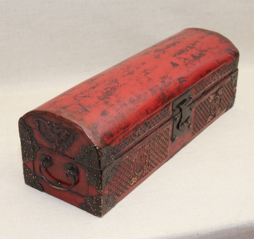 Domed Cinnabar Double-Handled Scroll Box of Lacquered Vellum and Wood with Ornately-Carved Front Panels, Reinforced Metal Corners and Latch, and Decorated End Panels with Classic Phoenix Motif.  China, Early 19th Century.<br />
<br />
22 inches