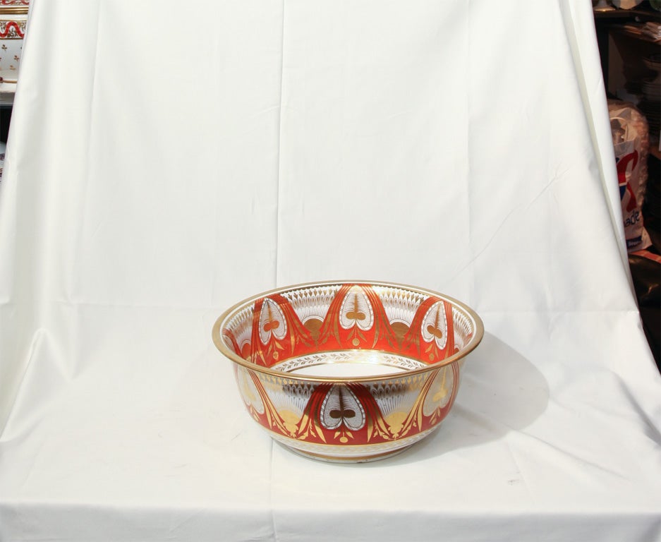 A Spode punch bowl with a strong geometric pattern of alternating, gilded stiff leaves and palm leaves resting on an orange ground.