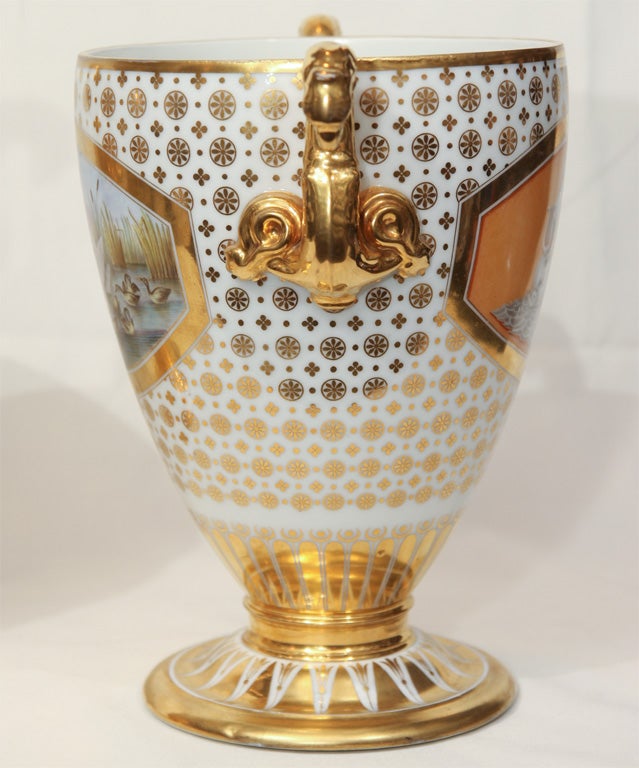 A Pair of gilded urns has mythological scenes. On one, Leda and the Swan, on the other, Apollo with his lyre. <br />
On the reverse each vase shows a contrasting contemporary scene of nature. One presents a family of swans swimming. The other a