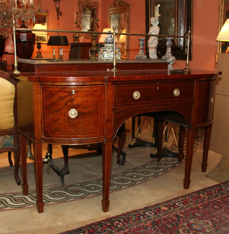 George III (Hepplewhite) mahognay satinwood inlaid 'D' form sideboard with brass plate rail on tapered legs.