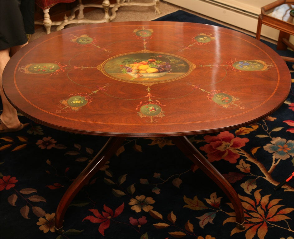 A magnificent oval mahogany breakfast or center hall table with fruitwood and string inlay. The top is exquisitely hand-painted at a later date and signed by the artist, depicting detailed still-life paintings depicting fruit specimens and an