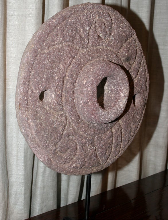 Grinding stone wheel on metal stand.  Pink/gray stone with decorative carvings.  Simple but substantial in style. Medium size.  Larger and smaller sizes available.