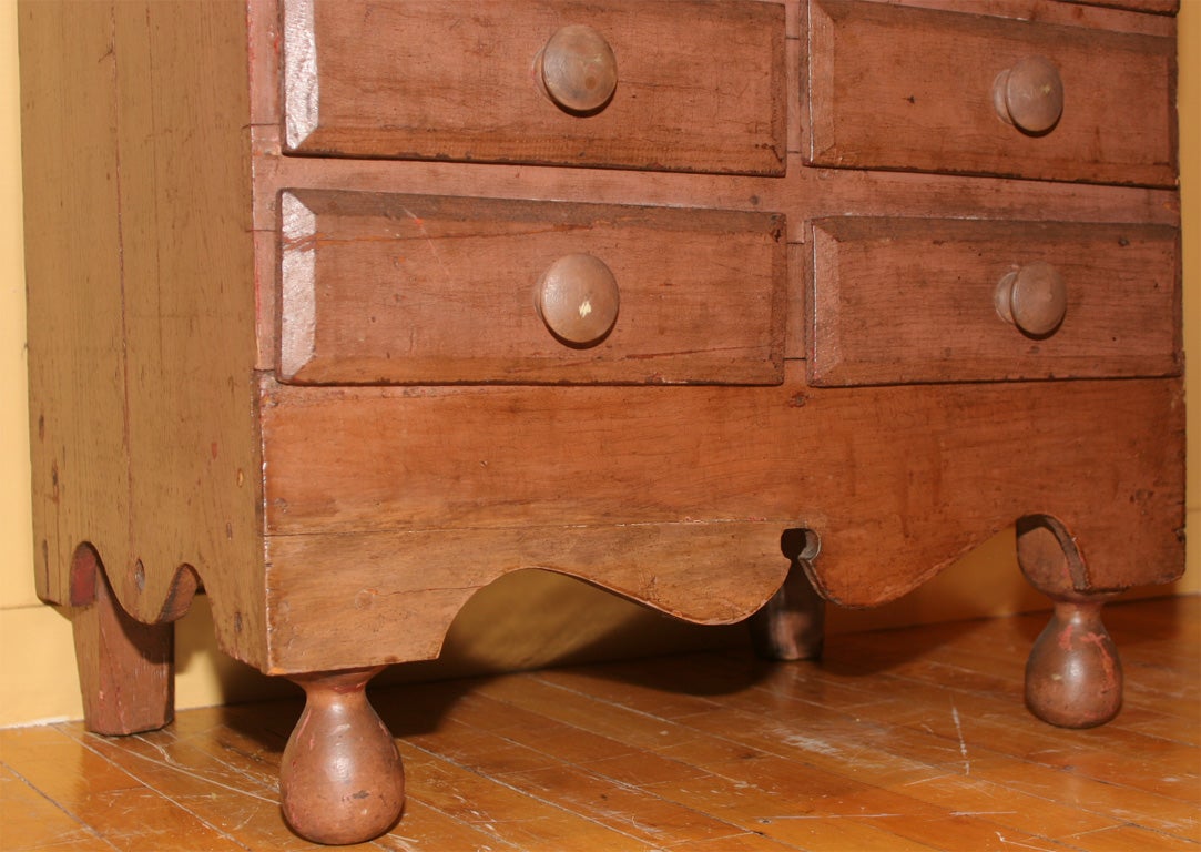 Folky child's step-back cupboard.  Late 19th Century.  Original salmon paint.  Six drawers and two doors with glass.  Scalloped base with ball feet.