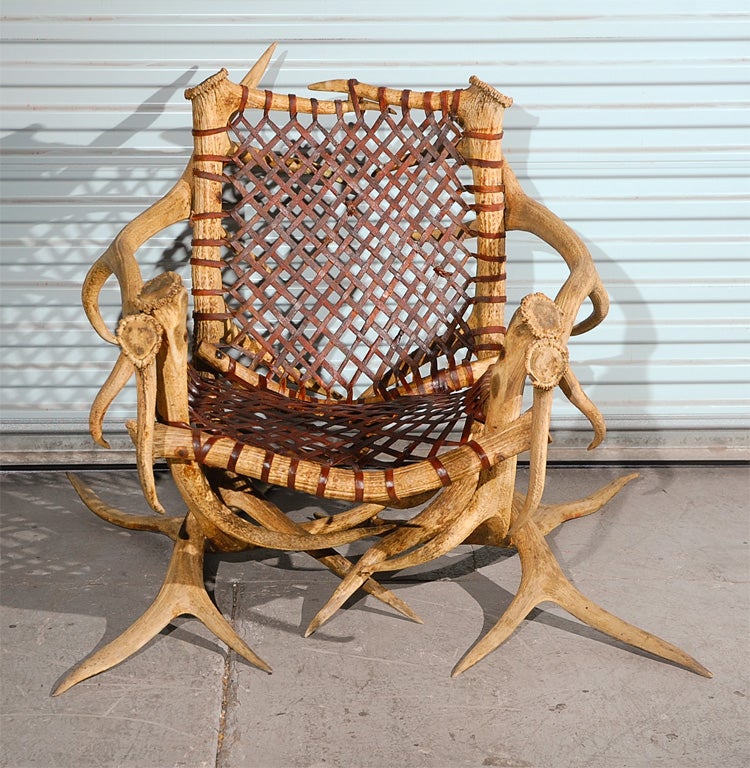 Three antler armchairs with leather strapping, signed.