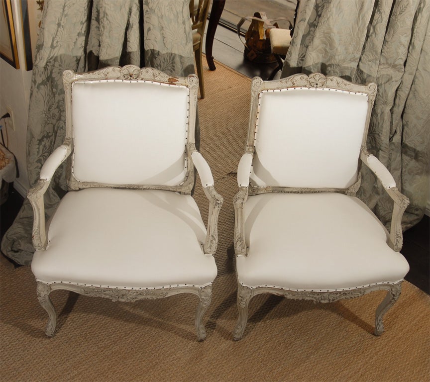 This pair of 19th century French bergere chairs, painted in a soft gray, this ornate frame takes on a Swedish feel. Newly upholstered in white cotton duck cloth to match any interior! Seat height 16