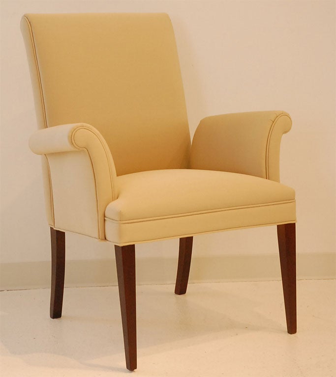 Handsome pair of scrolled arm chairs designed by Tommi Parzinger, recently reupholstered in a cotton/silk blend shot through with gold lurex.  The gracefully curving legs have been restored to a warm walnut finish.