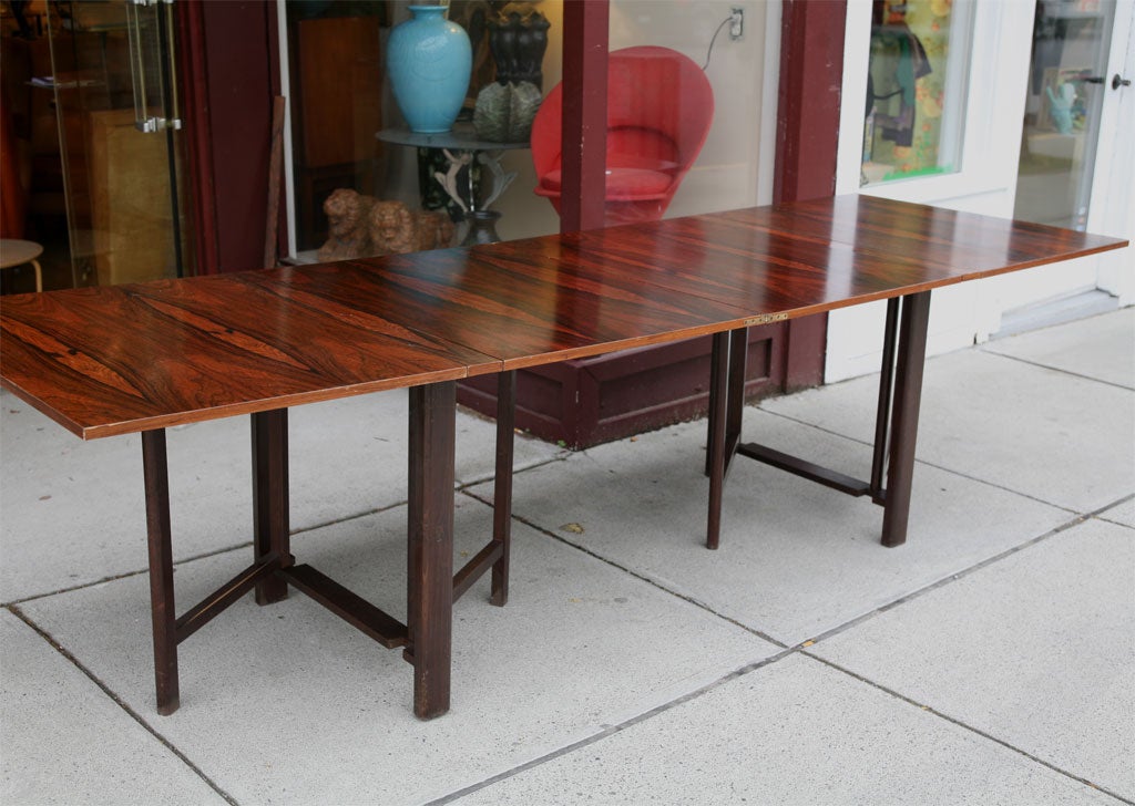 Long rectangular folding table by Swedish designer Bruno Mathsson in striking Brazillian rosewood.   This versatile table can be used in drop leaf form or a gate-leg form, or fully extended rectangular.  It measures 9
