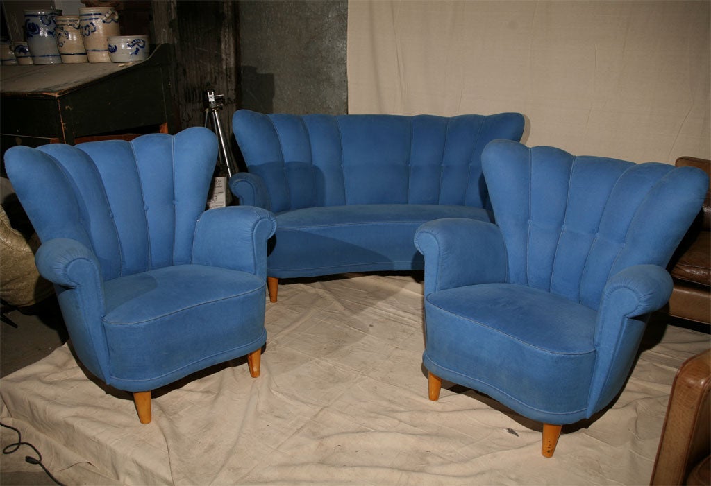 Three piece sofa suite comprising sofa and two armchairs upholstered in blue with channelled backs, short wooden tapered legs,  Sofa measures 62 inches long