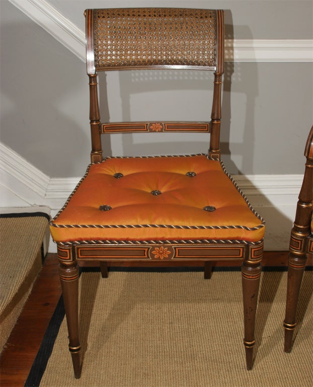 A very fine set of ten antique polychrome decorated dining chairs with caned scrolled table top rail above turned stiles joined by a bar, the armchairs with downswept arms, above a caned seat and squab cushion, on turned tapering legs. Nine chairs