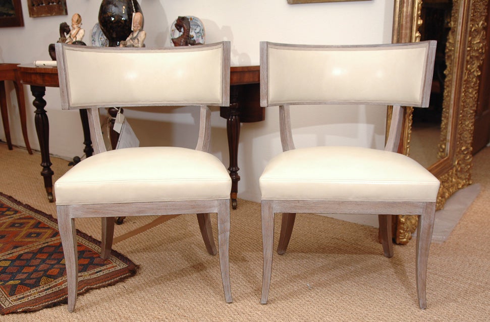 a pair of Klismos chairs copied from a pair of 1940s originals, white oak with a French wash, upholstered in ivory leather and trimmed with striped tape