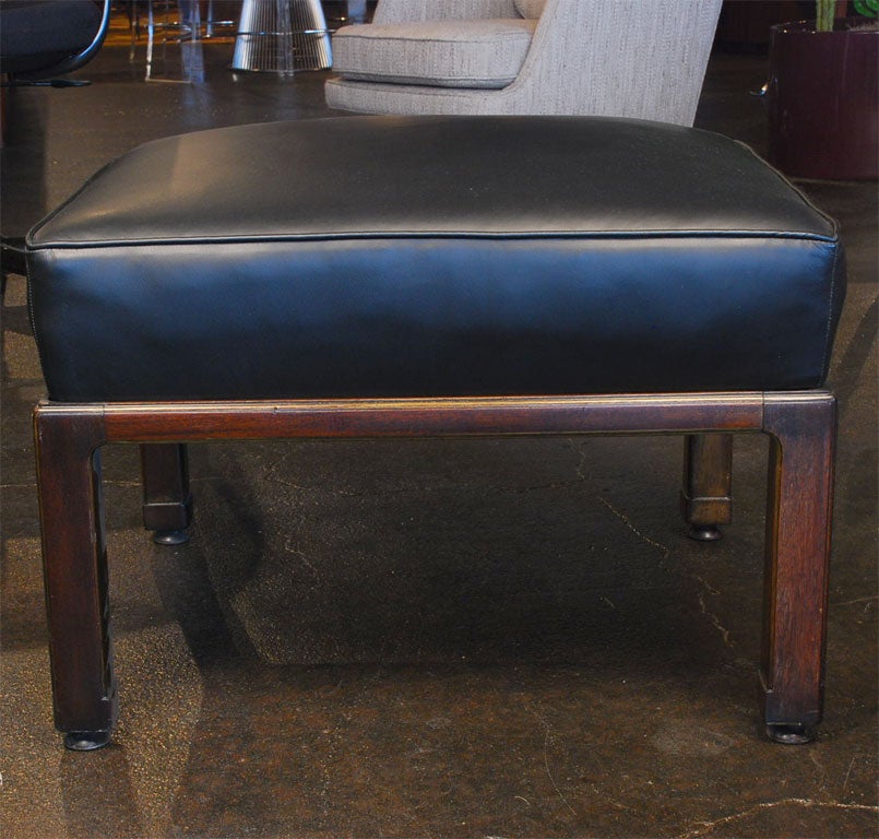 Classic mahogany ottoman upholstered in black leather. By Edward Wormley for Dunbar.