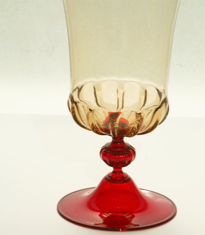 This wonderful Venini hand blown optic rib topaz vase blends the earthy topaz body with a contrasting ruby foot and knop. Clean and elegant lines make this example stand on its own as a functional vase as well as a perfect piece of sculpture on