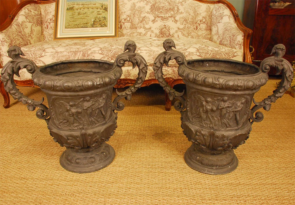Pair of Continental lead urns with scroll handles, neoclassical figures, shells, acanthus leaves and other neoclassical details.