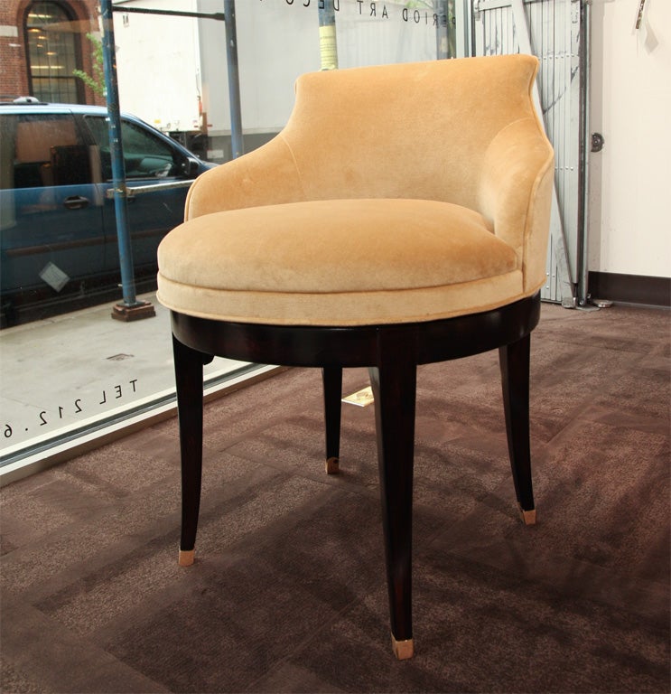 Elegant vanity stool with low back<br />
and slightly winged sides. Newly <br />
upholstered in a camel colored<br />
velvet with brown mahogany base<br />
and legs, with swivel seat and<br />
antique brass capped feet details.