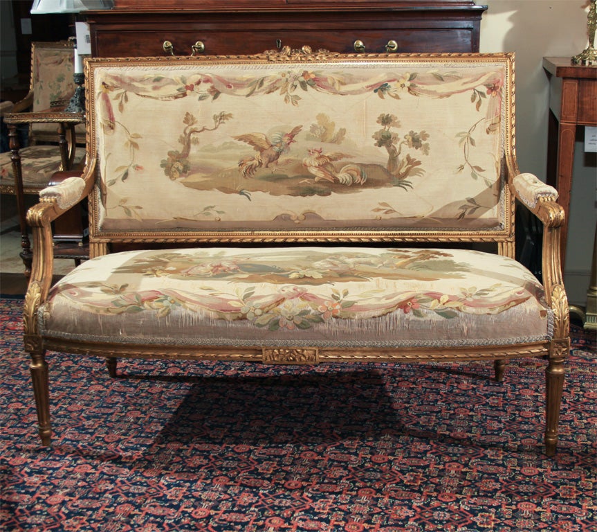 Louis XVI style salon set: settee and two armchairs. Gilt, with original Aubusson tapestry upholstery, animal and floral motif on chairs, and scenes from French writer Jean de la Fontaine's stories (written for the son of Louis XVI) on settee.