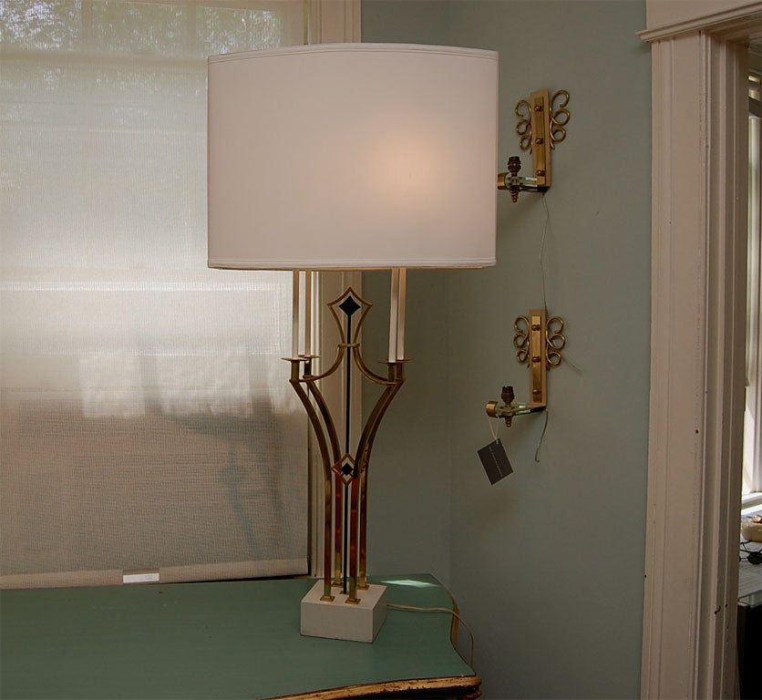 Four-light table lamp in brass and iron mounted on a white painted base; the socket supports suggesting candelabra; backed white linen shade; measurements include shade.