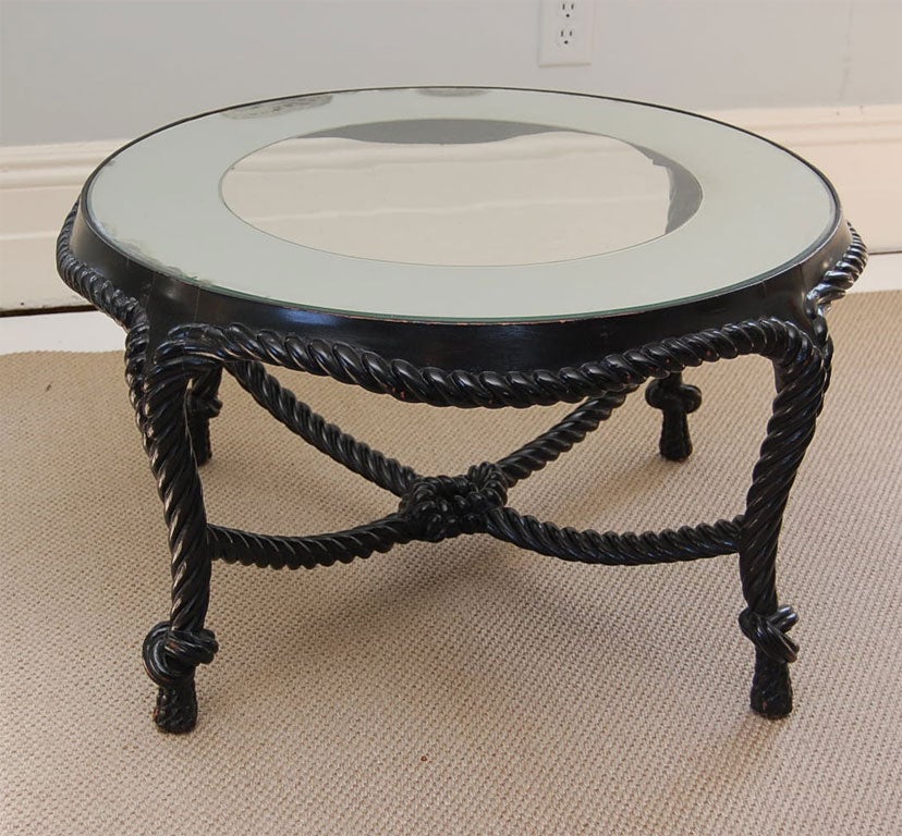 Circular coffee table in ebonized wood, carved to resemble rope; the draping stretchers 