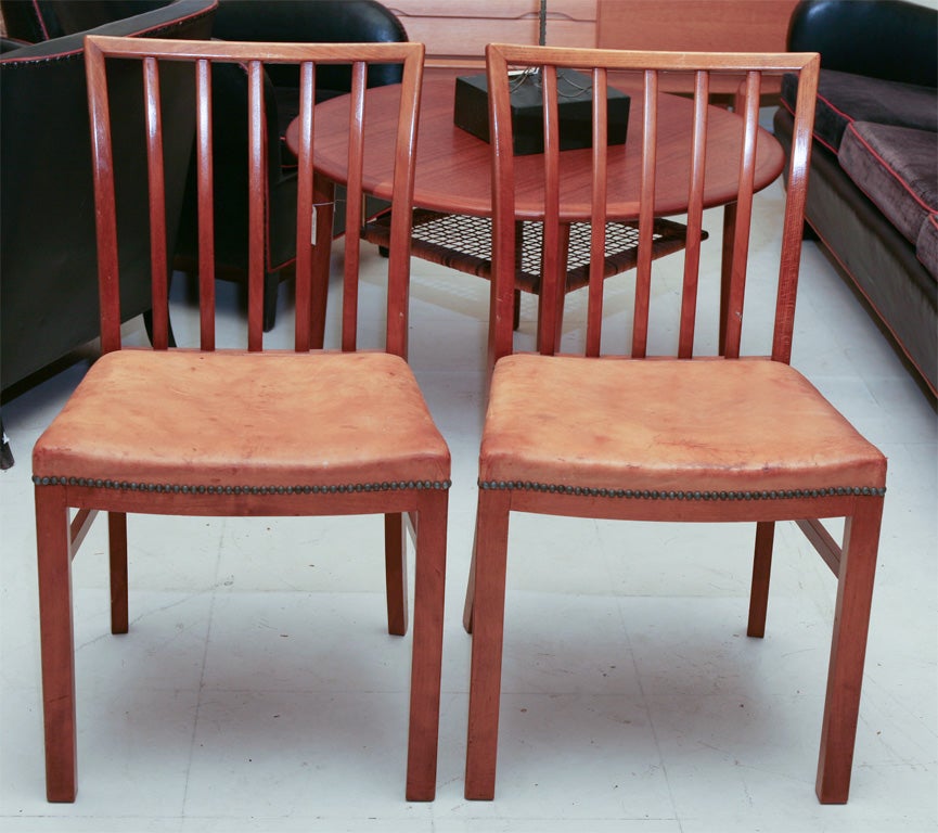 Elegant pair of Danish modern side chairs in the manner of Kaare Klint with curved seat in light brown leather, mid-20th century in mahogany.