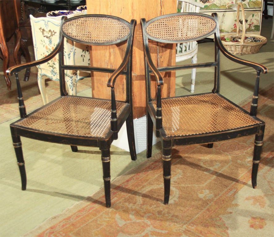 Pair of fine English Regency period black lacquer elbow chairs with cane seats and backs. Original paint.