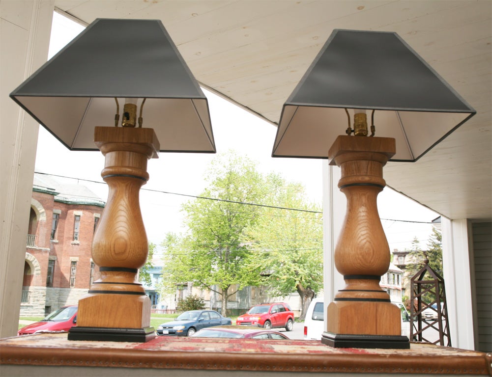 A nice pair of turned oak baluster-shaped lamps. The finish is in a clean clear light color and the lamps are accented with a small black detail with lacquered black bases and black shades.<br />
We purchased these as just wooden objects, had them