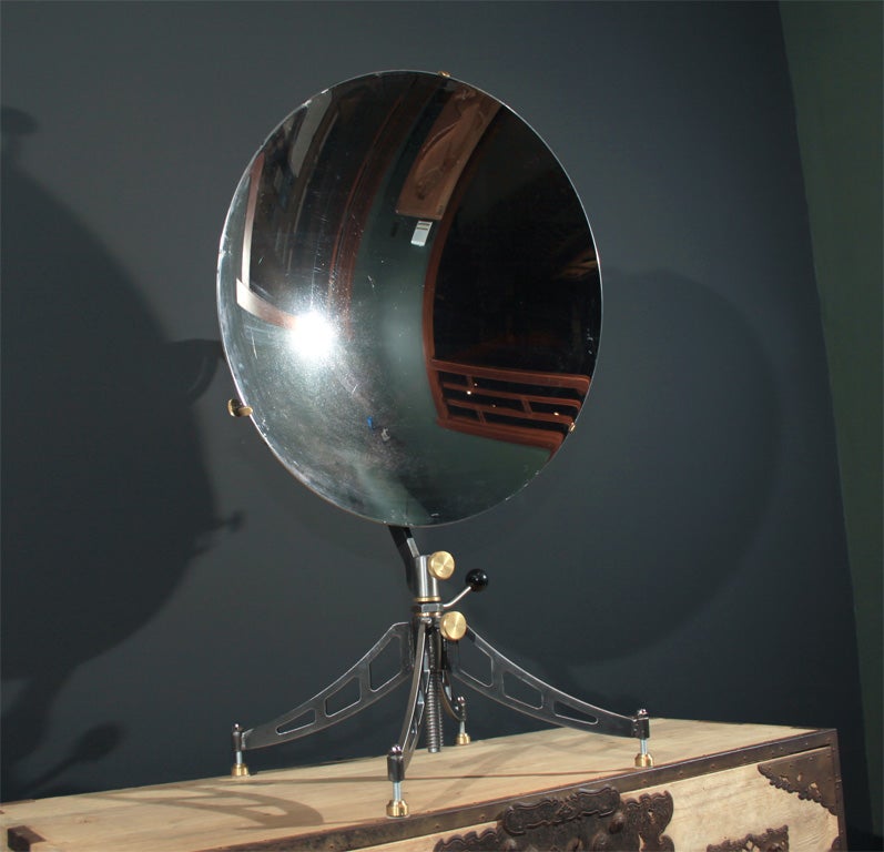 A massive concave mirror of military design possibly for use as a reflector from naval signal light, on a contemporary metal stand.  With marks on the reverse from the US Navy and its manufacturer Bausch and Laum. The mirror with minor scratches and