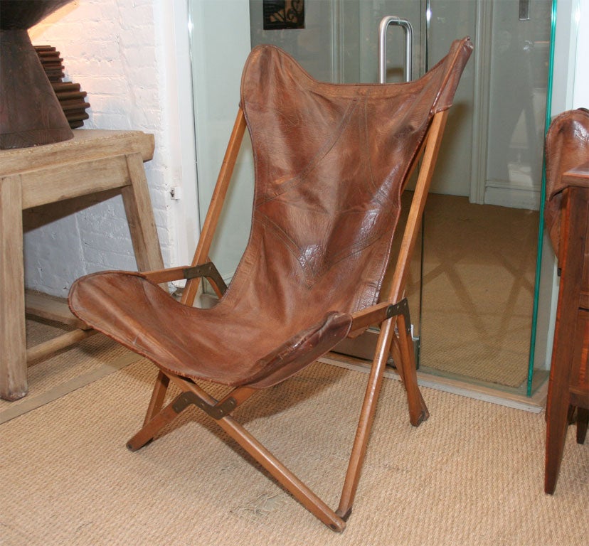 A pair of English leather campaign chairs, with teak frame, brass mounts and leather seats.