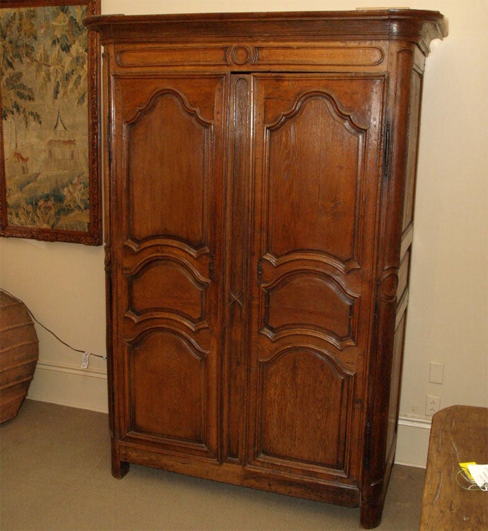Louis XIV armoire with raised paneled doors, sides, and rounded corners ending in stile feet.