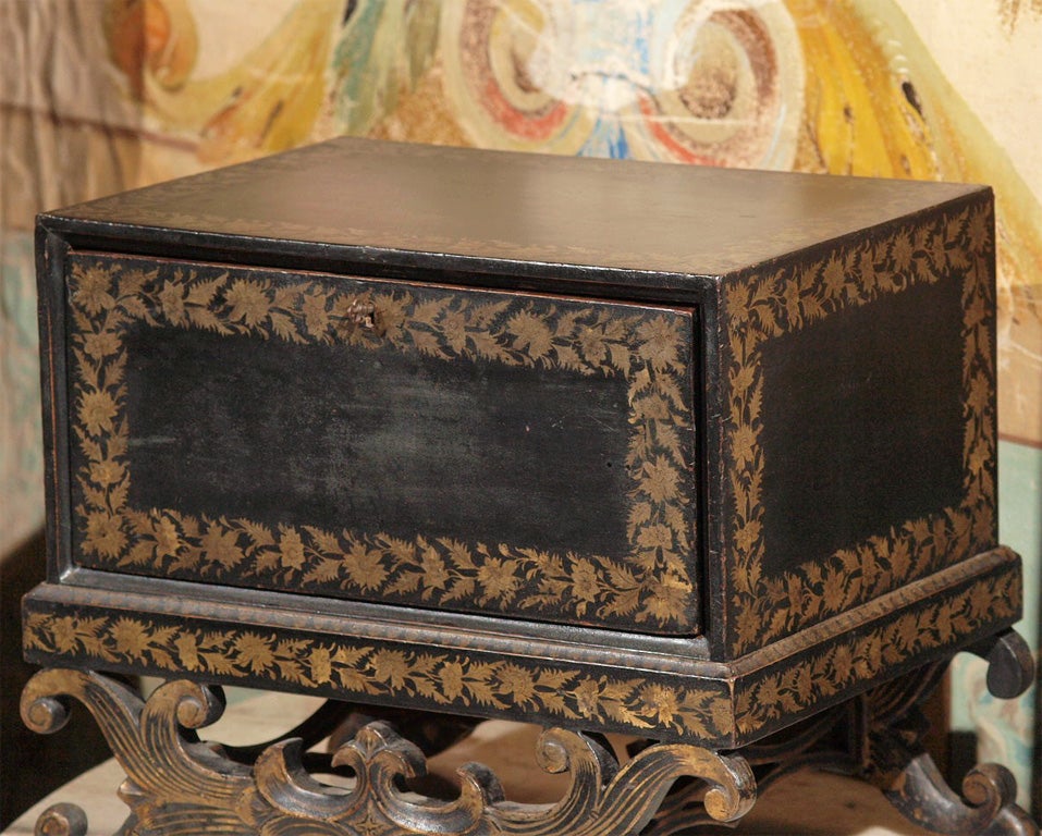 This 19th century tea chest / caddy is black lacquer with hand painted gold decoration. It's on the original stand and retains most of the original foil in the tea containers.