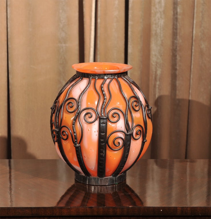 This is a beautiful example of a signed Lorraine vase, circa 1930's. Made of a mottled orange and white glass which appears to be coming through the decorative iron casing The glass has that translucent quality, very nice large size.