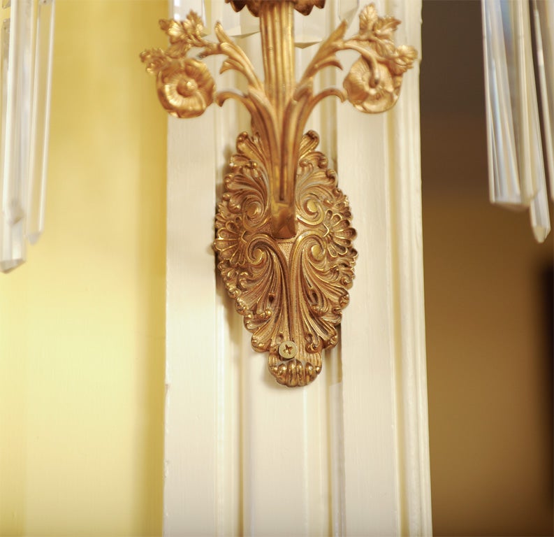 Pair of elegant girondole wall sconces, made by either Dietz of New York or Cornelius of Philadelphia.  Shell and scroll oval wall plate with floral and leaf decoration on stem terminating in acanthus bobeches hung with broad spear-tipped prisms (or