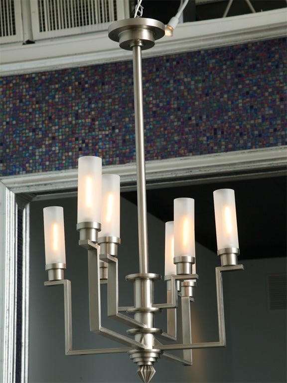 The central steel column with concentric rings and stylized acorn eminating turning arms with bobeches and tubular glass.