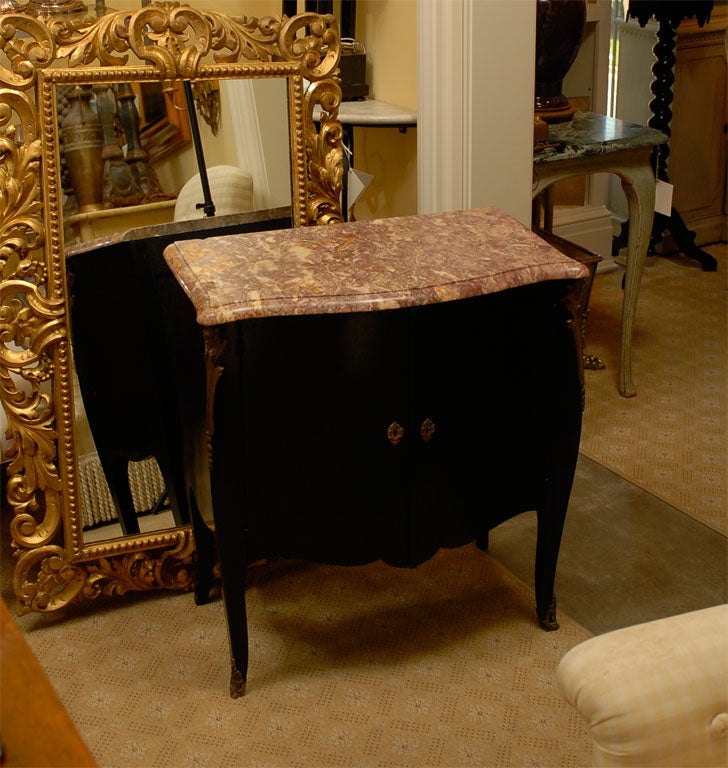 20th century French Louis XVI style transitional marble-top ebonized commode
Features two drawers inside that slide out, brass escutcheons with key and front corner ormolu mounts with devilish face.