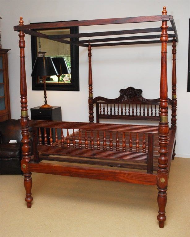 A dramatic, very hard-to-find British Colonial Queen size bed with four turned posts and a beautifully carved shell motif headboard and footboard with a later-made removable wooden canopy.  Mattress rests directly on the slats or it can be altered