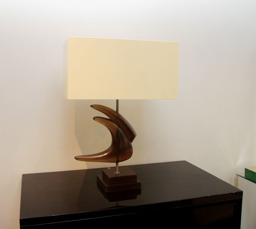 Nothing on earth like it, two abstract wings are sculpted in honey-colored resin, mounted on a metal stem over a resin stair-step pedestal. This rare lamp is complete with its original sockets. The shade is also unique in ivory-colored acrylic.