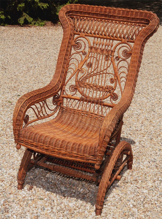 Intricately woven Victorian wicker platform rocker having lyre motif with multiple beads, curlicues & twisted reeding.  Decorative headrest of looped double reeds.  Elaborate detail under rolled arms and platform base. Gently curved solid woven seat.