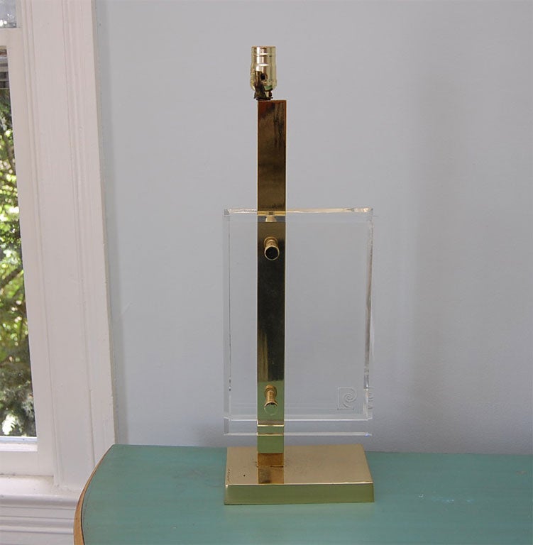 Table lamp in brass and Lucite bearing the Pierre Cardin logo; two beveled Lucite plates attach to a square brass support