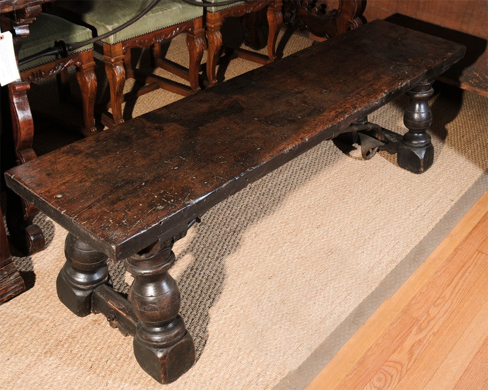 Spanish walnut bench with solid plank top and wrought iron trestle support from the 18th century.