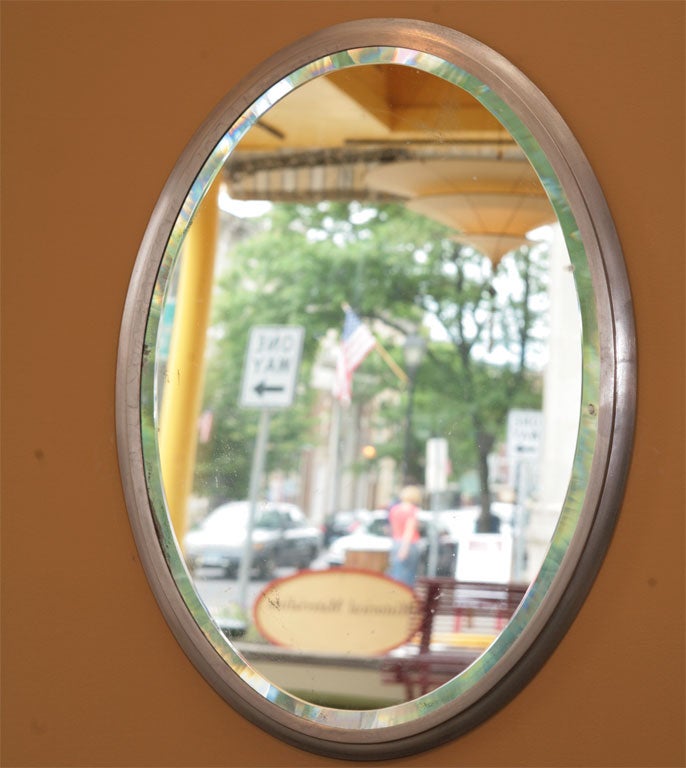 Oval mirror with beveled edge and satin- nickeled framing. Signed by the Brasscrafters Co. Unusual, large size, with a strong border.