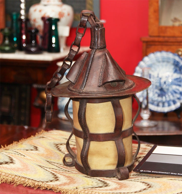 English Arts and Crafts period hand-stitched leather and parchment hanging lantern, constructed with two-tone copper hand-wrought copper rivets, and having original leather chain.