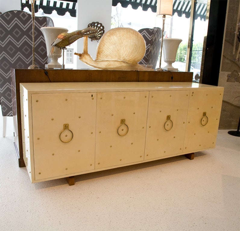 Handsome custom credenza designed by Italian designer Aldo Tura, covered in lacquered parchment with gold plated studs and ring pulls.<br />
<br />
The four door front opens up to reveal glass shelves, and the credenza sits atop sculpted Mahogany