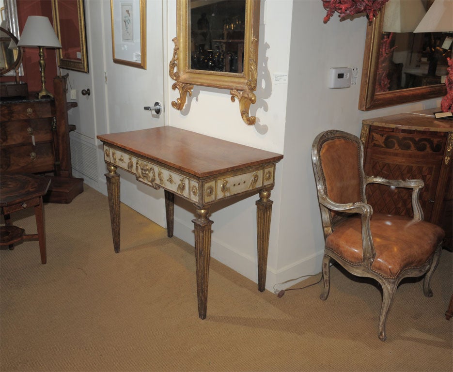 Italian Neoclassical console with mecca gilt and cream ground. The top faux marbled.  Made late in the 18th century or early in the 19th century.  Featuring  mecca gilt pelicans and masks.  Standing on fluted tapered  legs.  The faux marble top has