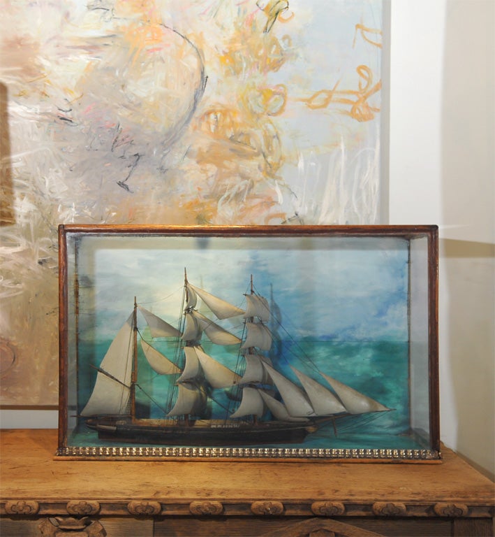 Handcrafted English Ship Diorama encased in a wood framed glass box with hand painted backdrop in soft blues and greens.  The box base has a decorative trim.