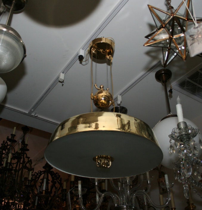 A signed Paavo Tynell for Taito lacquered brass ceiling light with star shaped perforations and frosted glass plate on underside secured by signature wire loop “poof”. The fixture secured to original ceiling plate and pullies by cables with
