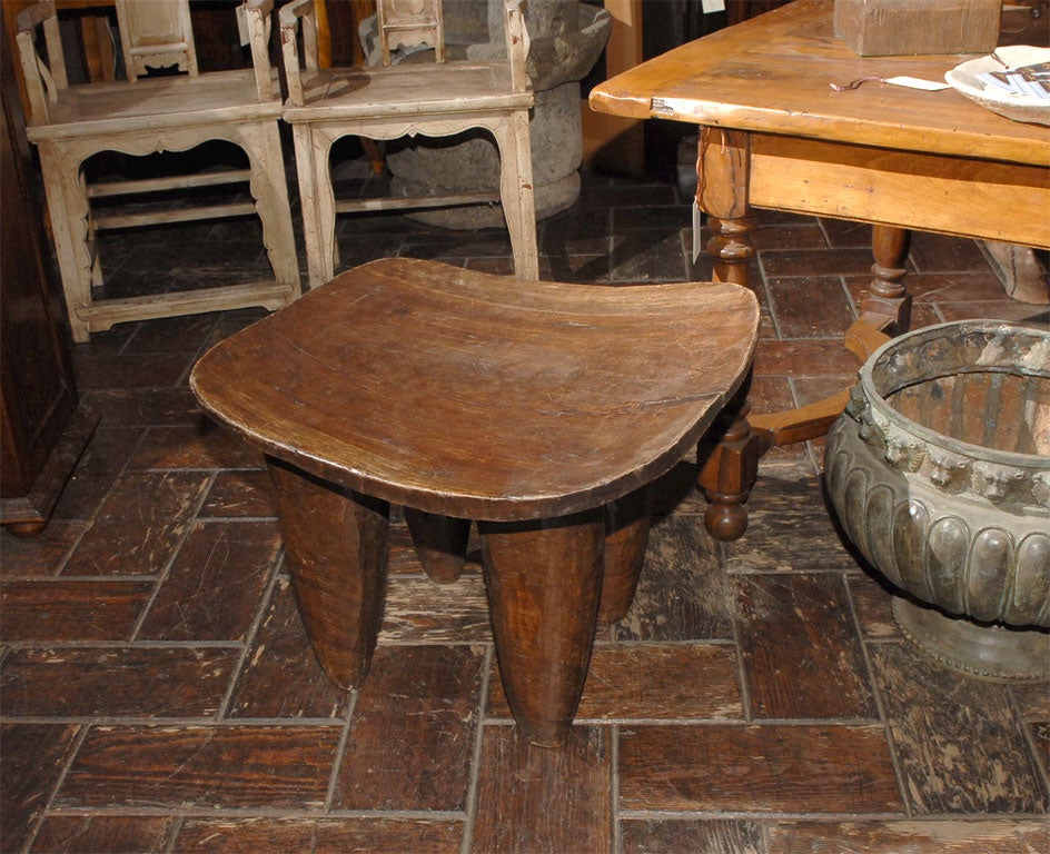 Primitive stool used by chieftain. Torpedo like legs supporting a scooped curved top surface. Very sculptural.