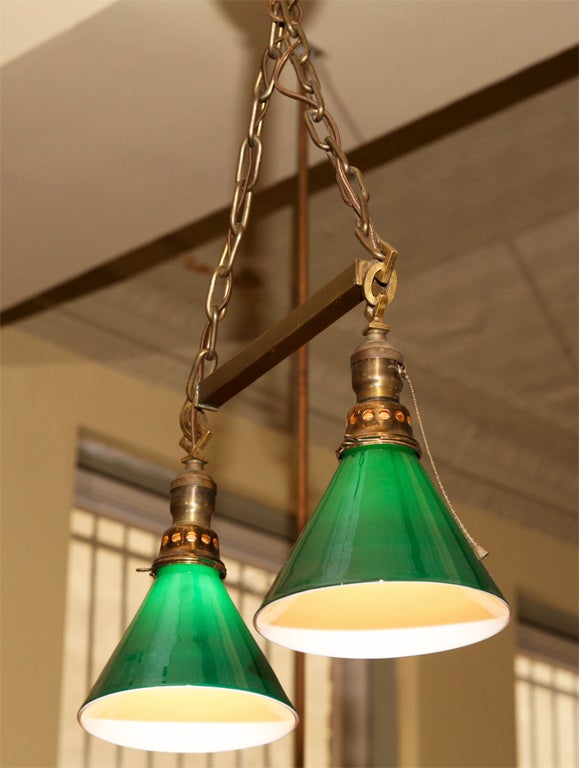 Early electric fixture with simple brass chains and square tube rod supporting two green and white cased- glass shades. Includes original ceiling canopy. Restored and rewired.