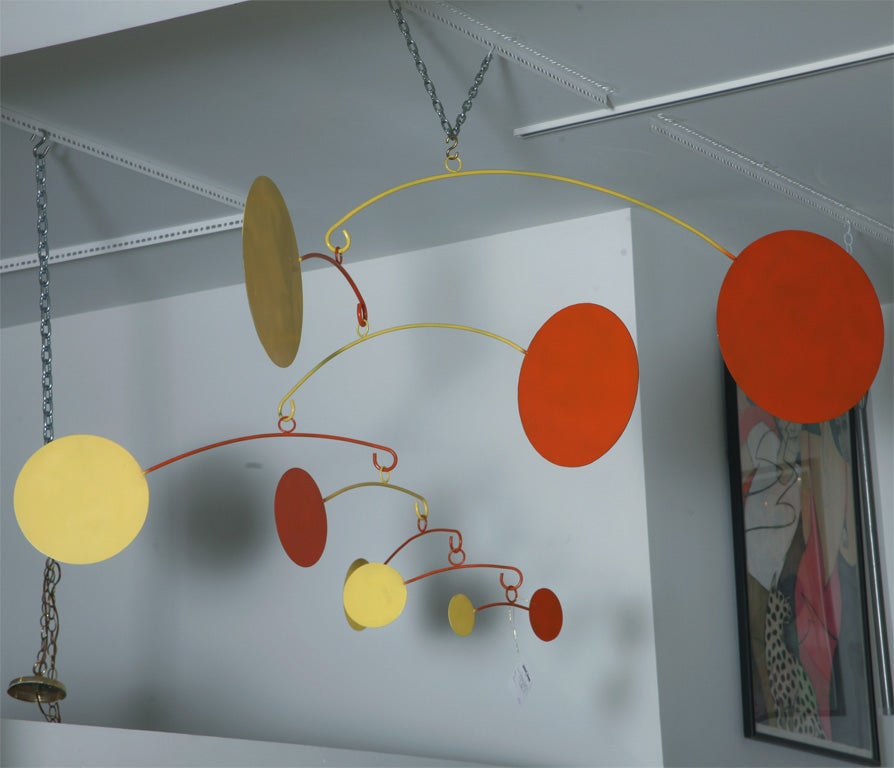 Geometric orange and yellow sculpture in the manner of sculptor Alexander Calder with many pivoting arms.