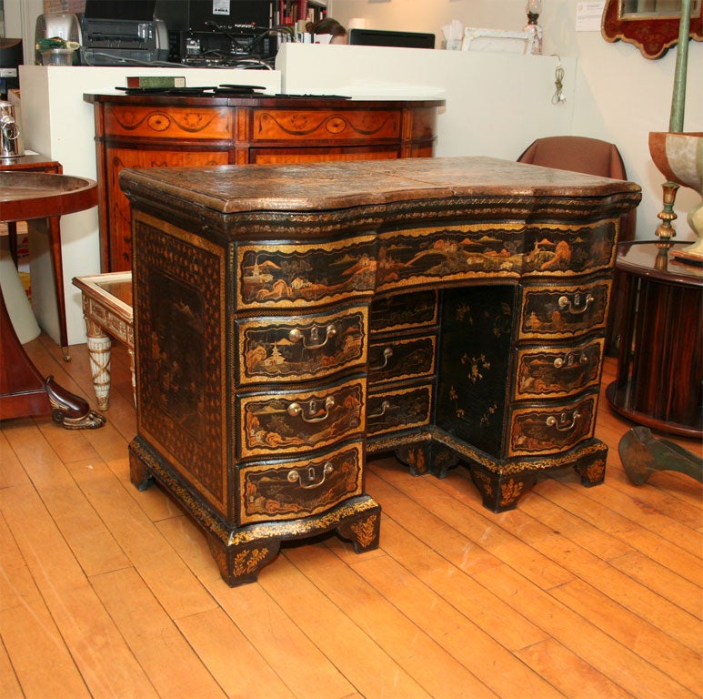 The japanned top depicting a genre scene opening to reveal 14 cabinets and a rising rear mirror. The serpentine front having a kneehole flanked by three drawers on either side ending in ogee feet.  Some restoration to lacquer.