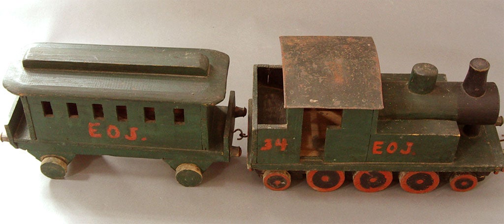A wooden locomotive and passenger car make up this toy train from Sweden, circa 1880. It is painted green with orange highlights around the wheels, and with the initials 